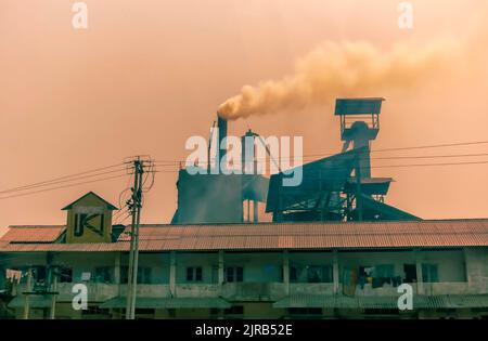 Fumée sombre à la suite de la combustion du charbon dans des fours, qui s'échappe de cheminées dans une usine de ciment à Byrnihat, Meghalaya, en Inde. Banque D'Images