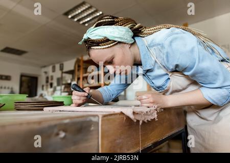 Jeune potier avec outil à main travaillant dans un studio d'art Banque D'Images