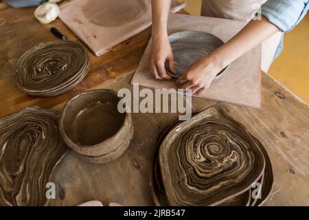 Mains de potter plaque de fabrication avec argile sur établi Banque D'Images