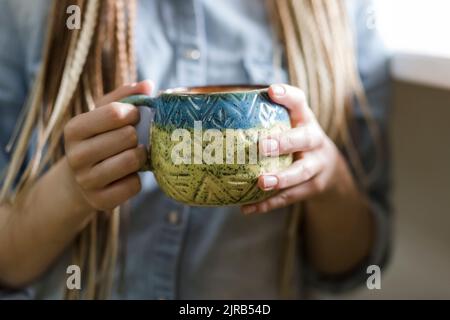 Mains de l'artisan tenant une tasse en céramique Banque D'Images