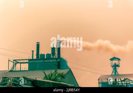 Fumée sombre à la suite de la combustion du charbon dans des fours, qui s'échappe de cheminées dans une usine de ciment à Byrnihat, Meghalaya, en Inde. Banque D'Images