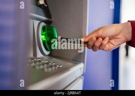 Main de femme utilisant une carte de crédit au guichet automatique Banque D'Images