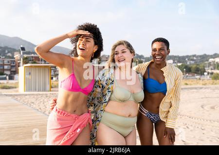 Femme qui protège les yeux marchant avec des amis à la plage Banque D'Images