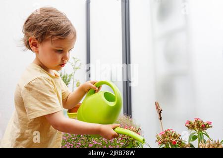 Garçon versant de l'eau sur les plantes par l'arrosoir Banque D'Images