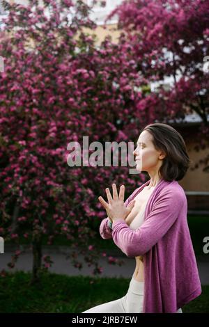 Femme aux mains claspéties faisant du yoga devant les arbres Banque D'Images