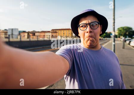 Un adolescent qui fait le visage prend le selfie dans la rue Banque D'Images