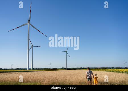 Père et fille debout près des éoliennes sur le terrain Banque D'Images