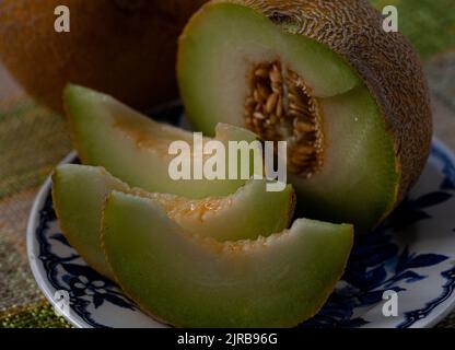 Tranche une moitié de melon sur une assiette bleue et un trou rond de melon à côté. Banque D'Images