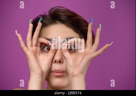 Jeune femme faisant un geste ok comme des jumelles avec les mains Banque D'Images