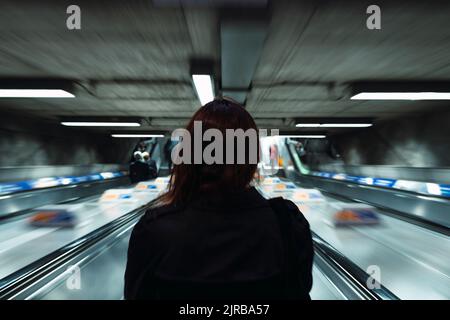 Jeune femme debout sur l'escalier roulant en train de descendre Banque D'Images