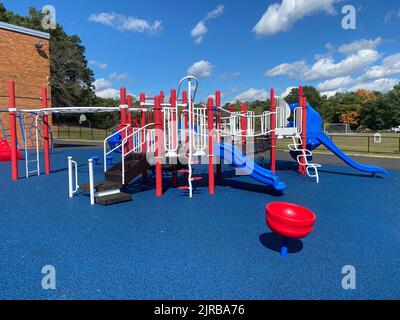 Aire de jeux typique non identifiée de l'école élémentaire avec surface de chute de sécurité en caoutchouc bleu Banque D'Images