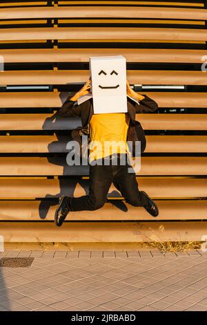 Homme portant une boîte avec un visage souriant sautant sur la piste Banque D'Images