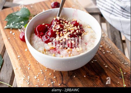 Porridge de petit déjeuner au millet avec compote de cerise et noix grillées Banque D'Images