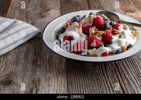 Yaourt aux baies et amandes grillées pour un petit déjeuner à base de glucides sur une table en bois. Vue avant Banque D'Images