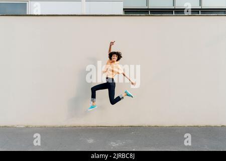 Une femme joyeuse sautant devant le mur Banque D'Images