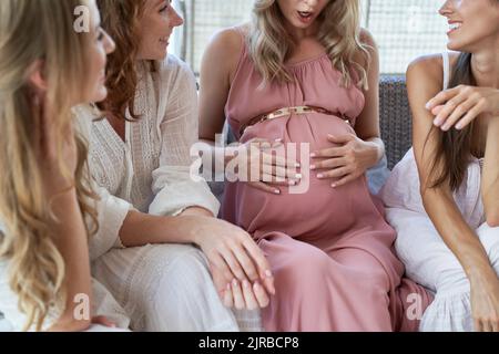 Surprise femme enceinte avec la main sur le ventre par des amis à la douche de bébé Banque D'Images