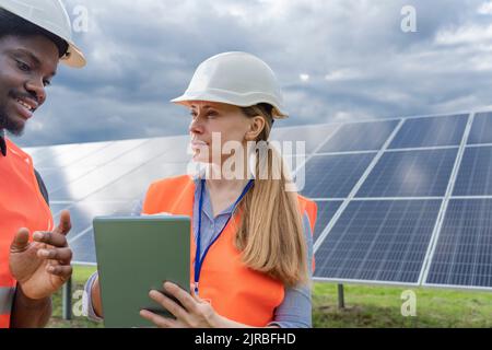 Les ingénieurs discutent au-dessus d'un Tablet PC devant les panneaux solaires Banque D'Images