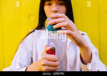 Jeune femme qui brûle la terre avec un allume-cigare Banque D'Images