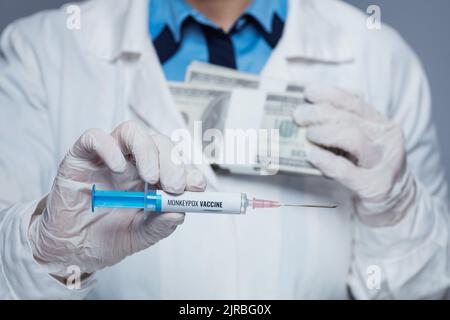 Gros plan sur le médecin moderne femme en robe médicale blanche avec seringue de vaccin contre la variole du singe et sac d'argent isolé sur le gris. Banque D'Images