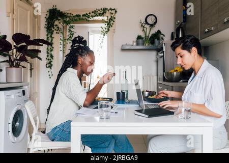 Jeunes femmes d'affaires prenant le petit déjeuner et travaillant à la maison Banque D'Images