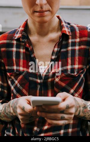 Femme avec messagerie texte tatouage par smartphone Banque D'Images