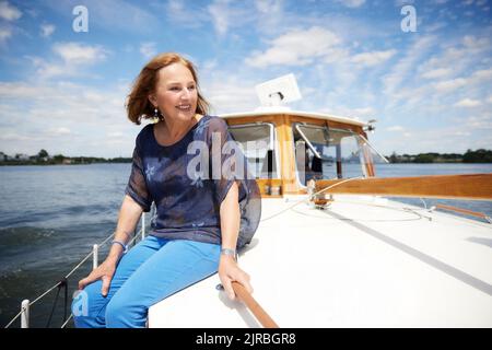 Bonne femme âgée assise sur la terrasse du bateau en vacances Banque D'Images