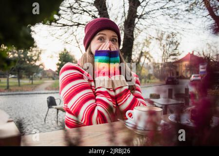 Femme surprise assise dans un café-terrasse Banque D'Images