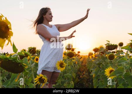 Femme souriante qui fait un geste sur le terrain de tournesol Banque D'Images