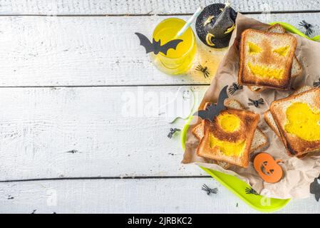 Nourriture drôle pour les enfants, petit déjeuner Halloween, boîte à déjeuner: Toast avec des œufs brouillés en forme de monstres et fantômes Halloween, sur table en bois avec déc Banque D'Images