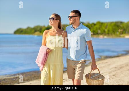 couple heureux avec panier pique-nique à pied sur la plage Banque D'Images