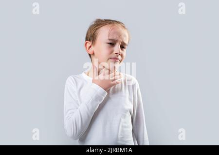 Le jeune garçon sent que sa gorge est douleur. Petit garçon malade avec mal de gorge. Enfant malade avec mal de gorge. Maux de gorge chez un enfant. L'enfant a une plaie Banque D'Images