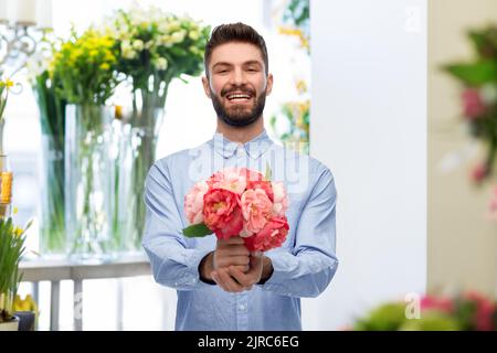joyeux homme souriant avec des pivoines au fleuriste Banque D'Images