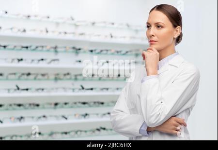 penser femme médecin en manteau au magasin optique Banque D'Images