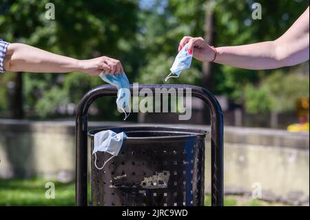 Jetez le masque dans la poubelle, le masque médical en main devant la poubelle, l'élimination des déchets médicaux Banque D'Images