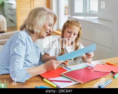 devoirs enseignement éducation grand-mère enfants petite-fille famille enfant enfant enseignant salle de classe ciseaux seniors créativité papier artisanat Banque D'Images