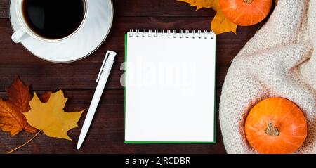 Concept du matin d'automne. Tasse de café expresso chaud et feuilles mortes sur fond de bois. Carnet, chandail et citrouilles en tricot pour mockup. Bannière pour Banque D'Images