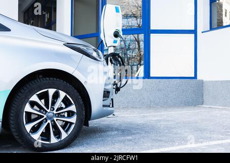 Une partie de la voiture dans le parking à côté de la station de charge Banque D'Images