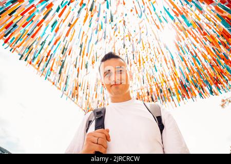 Un homme au festival regarde la caméra et sourit sur un fond coloré Banque D'Images