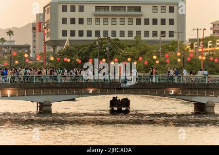 Tokushima, Japon - 12 août 2022 : un petit bateau passe sous un pont bondé au festival d'Amaodori Banque D'Images