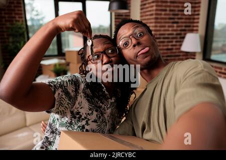 Les partenaires afro-américains se sentent gai à propos de la nouvelle propriété, tenant les clés de la maison familiale et se déplaçant ensemble. Les propriétaires célèbrent la réalisation de la vie et commencent de nouveaux débuts. Banque D'Images