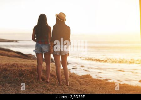 Tout était calme sur la côte. Vue arrière de deux jeunes amis tenant les mains à la plage. Banque D'Images