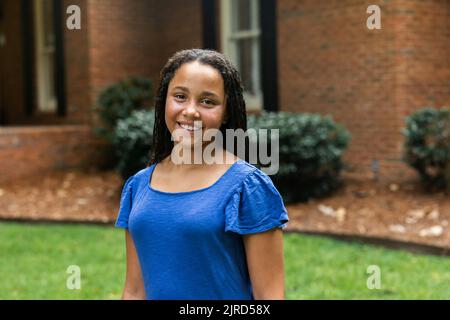Middle School filles âgées dans une robe bleue debout à l'extérieur de sa maison pour un portrait Banque D'Images