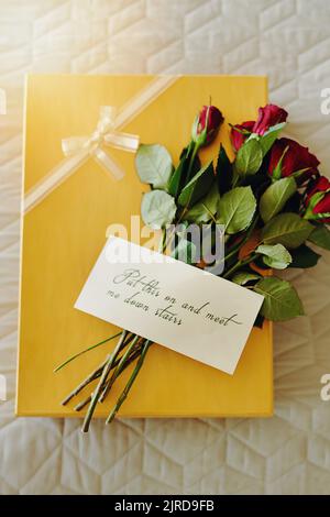 Un cadeau surprise et un bouquet avec une note qui lui est attachée. Banque D'Images