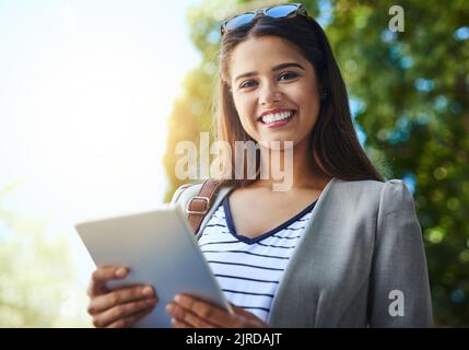 Les affaires ne s'arrêtent jamais, et moi non plus. Portrait court d'une jeune femme attrayante utilisant sa tablette lors de ses déplacements au travail. Banque D'Images