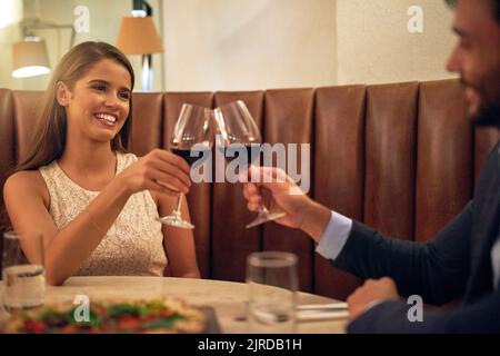 Les plus aimés sont les années remplies. Chaud d'un jeune couple heureux en dégustant du vin lors d'un dîner romantique dans un restaurant. Banque D'Images