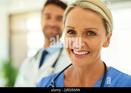 Mettez votre santé entre nos mains. Portrait de deux heureux professionnels de la santé se posant ensemble dans un hôpital. Banque D'Images