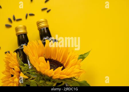 Huile de tournesol. Bouteilles d'huile, graines de tournesol noires éparpillées et tournesols fleurissant sur un fond jaune vif.maquette d'huile de tournesol. Organique Banque D'Images