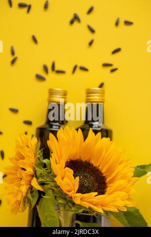 Huile de tournesol. Des bouteilles d'huile, des graines de tournesol noires éparpillées et des tournesols fleurissent sur une huile de tournesol de ferme naturelle jaune vif de background.Organic Banque D'Images