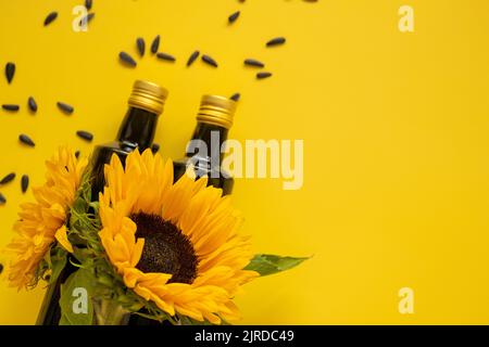 Huile de tournesol. Bouteilles d'huile, graines de tournesol noires éparpillées et tournesols fleurissant sur un fond jaune vif.maquette d'huile de tournesol. Organique Banque D'Images