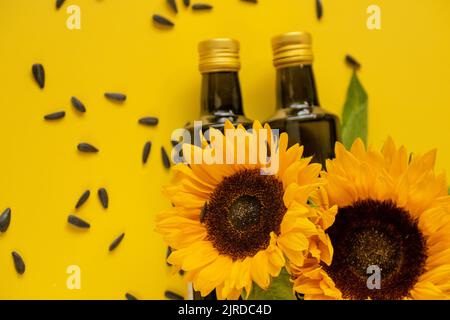Des bouteilles d'huile, des graines de tournesol noires éparpillées et des tournesols sur une huile de tournesol de ferme naturelle background.Organic jaune vif. Huiles comestibles. Banque D'Images